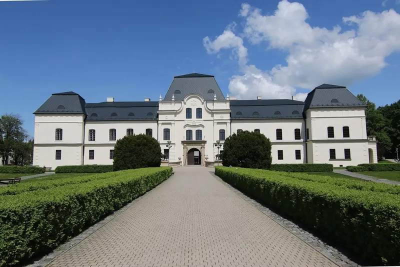 Biely kaštieľ v Humennom a dláždená alej s tvarovanými kríkmi vedúca k vchodu
